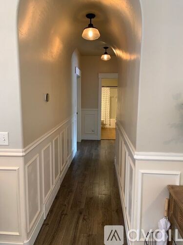 A hallway with wood floors and white walls.