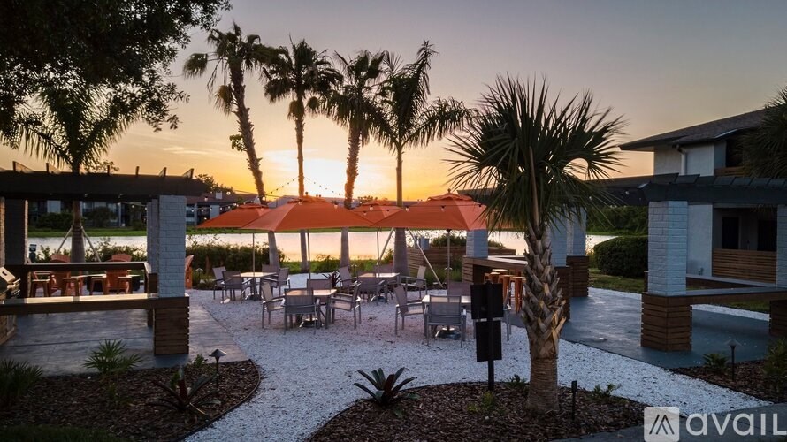 A patio area with a table set for dining surrounded by palm trees.