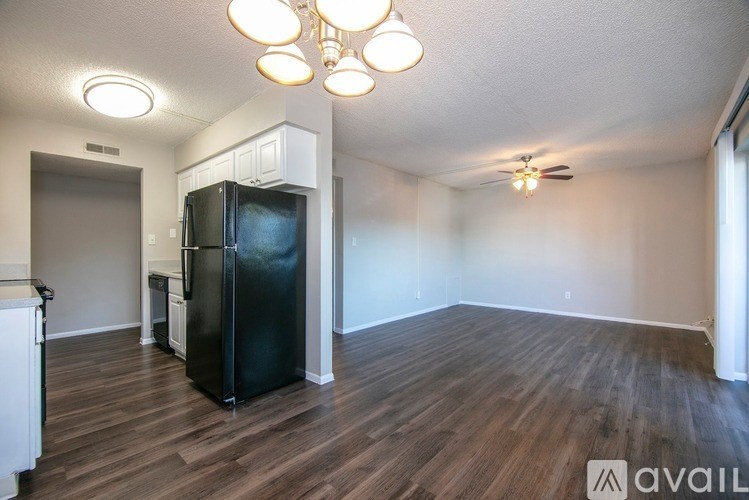 A kitchen with a black fridge and wooden floors.