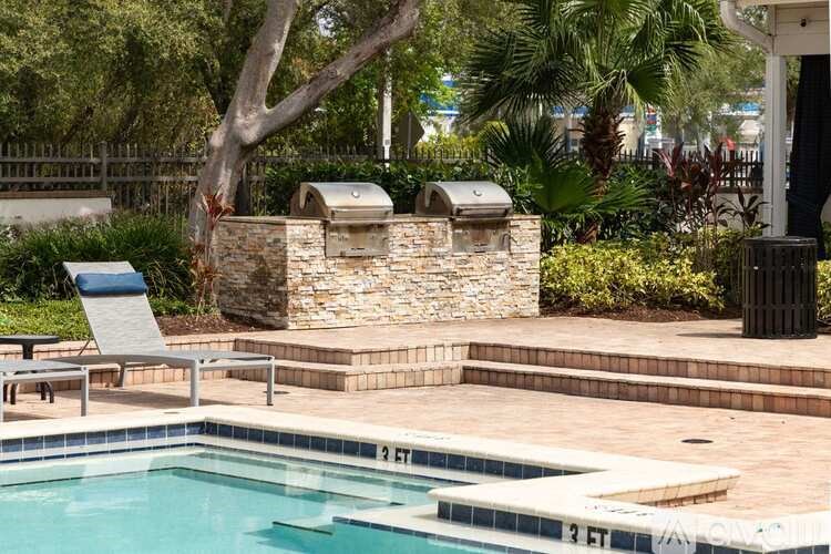 A pool with a stone wall and a tree in the background.