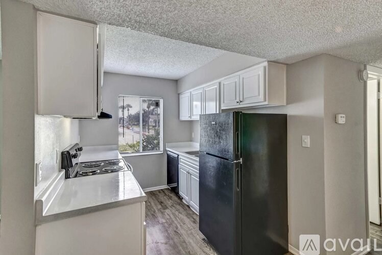 A kitchen with a black refrigerator and white cabinets.