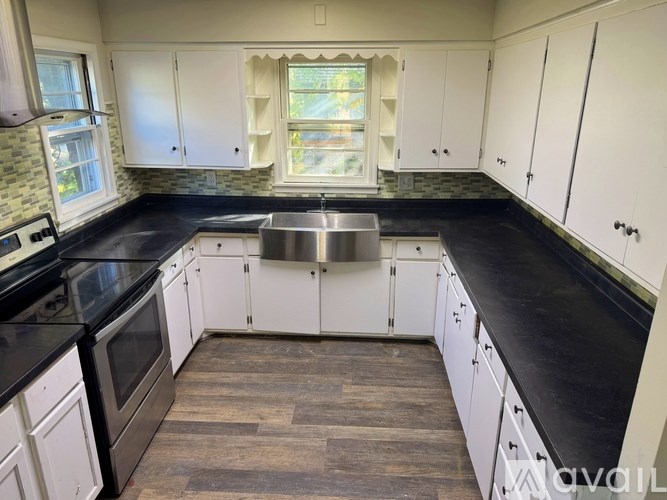 A kitchen with white cabinets and a black countertop.