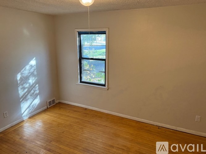 A room with a window and wooden flooring.