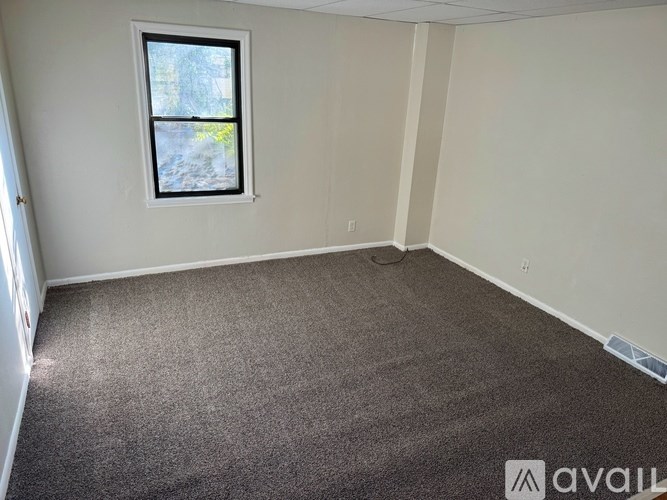 A room with a carpeted floor and a window.