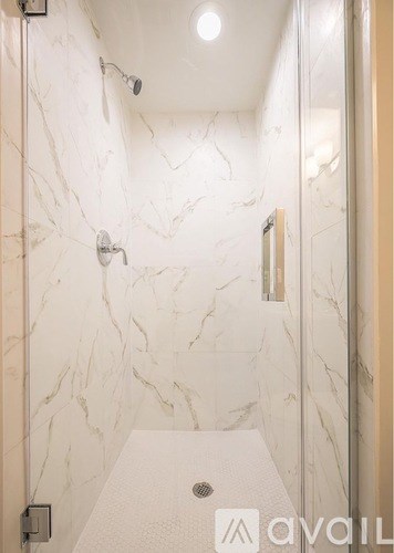 A white marble bathroom with a walk in shower.
