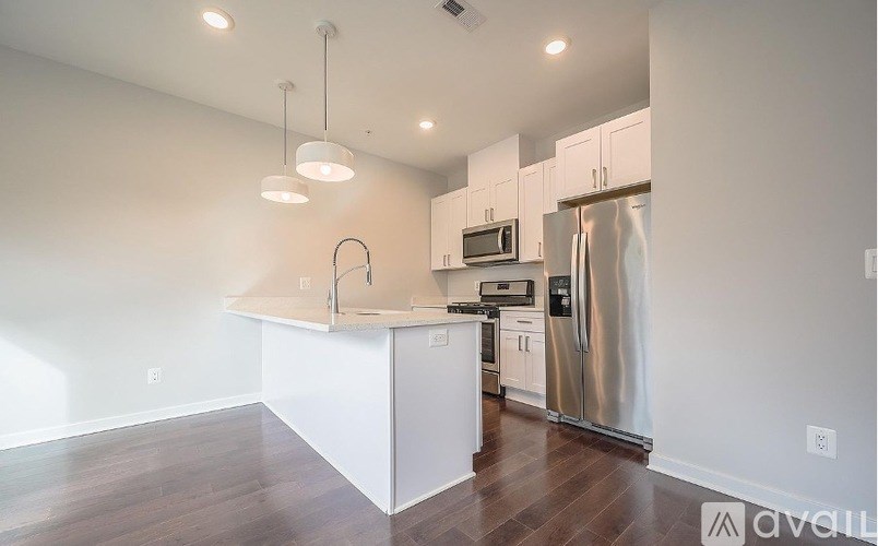 A kitchen with white cabinets and a stainless steel refrigerator.