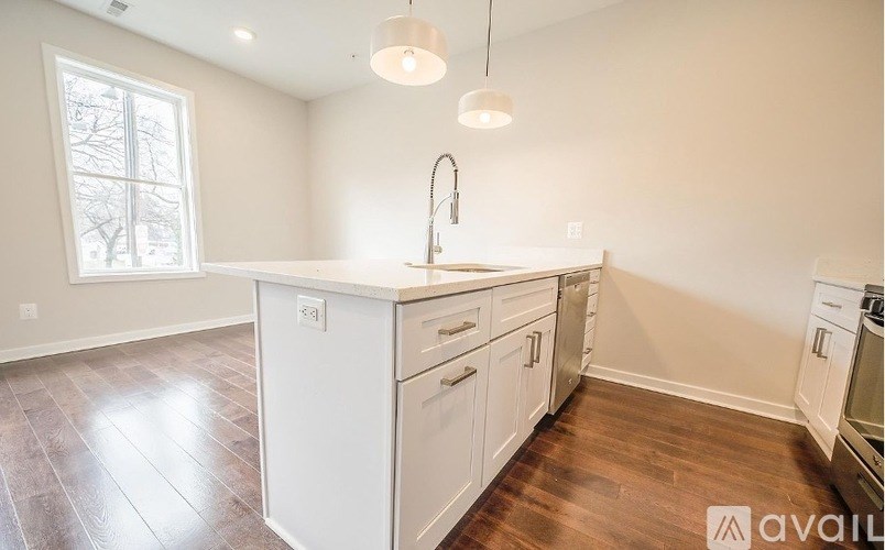 A kitchen with white cabinets and a wooden floor.