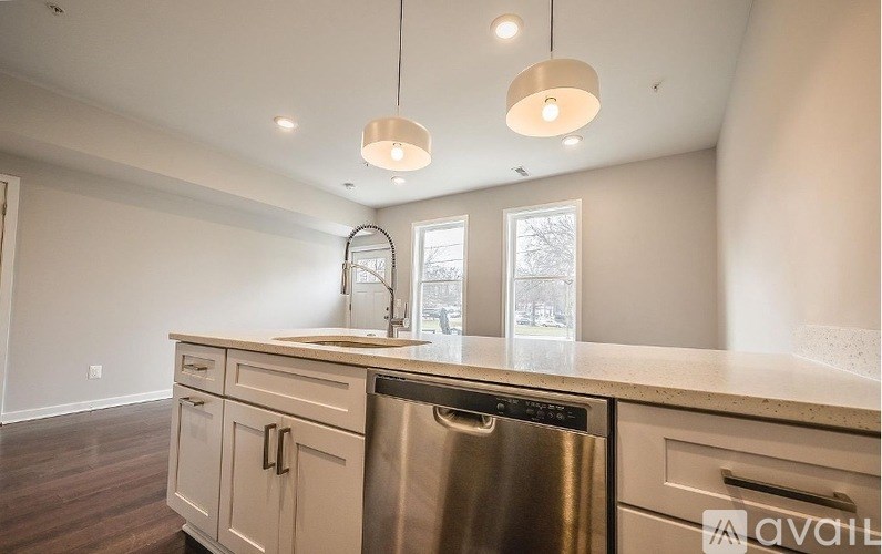 A kitchen with a stainless steel dishwasher and wooden cabinets.