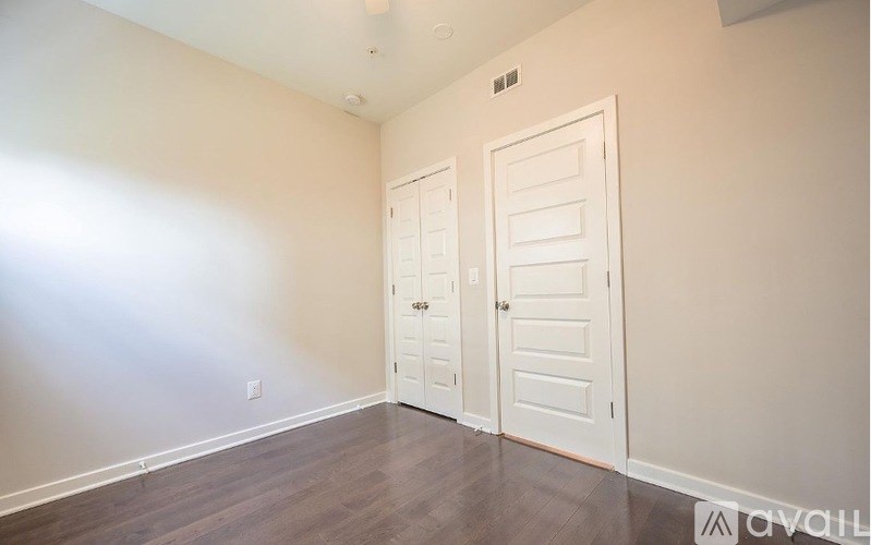 A room with two white doors and wooden flooring.