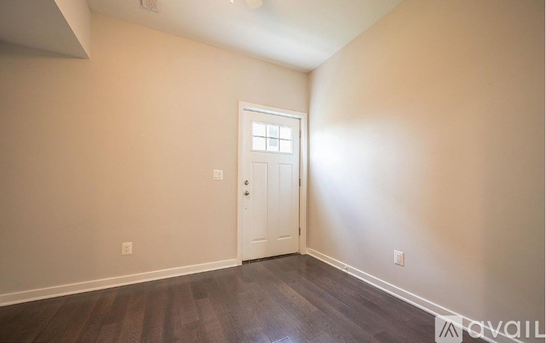 A room with a white door and wooden flooring.