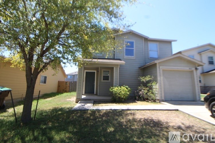 A house with a grey front yard and a tree.