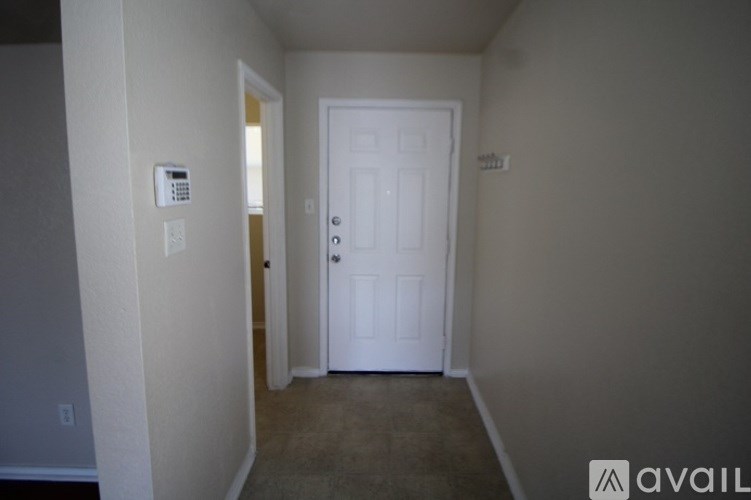 A hallway with a door and a wall-mounted phone.