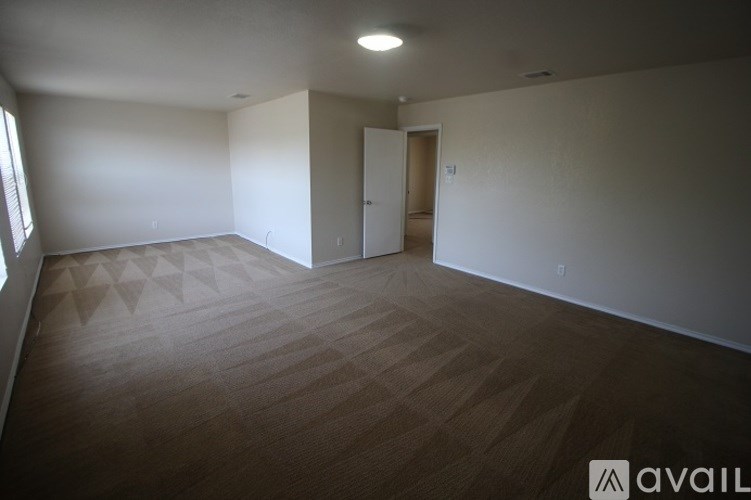 A room with a wooden floor and a white wall with a door.