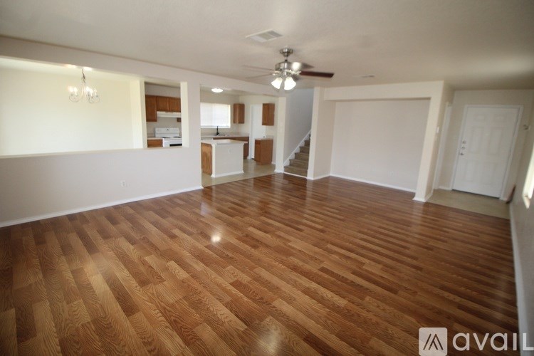 A spacious room with wooden flooring and a ceiling fan.