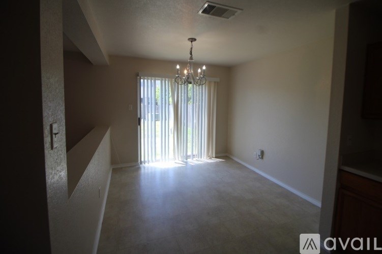 A room with a chandelier and a window with curtains.