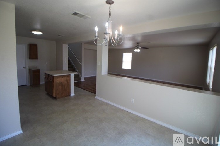 A large, empty room with a chandelier and a wooden cabinet.