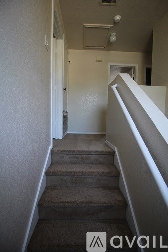 A hallway with a staircase leading to a door.
