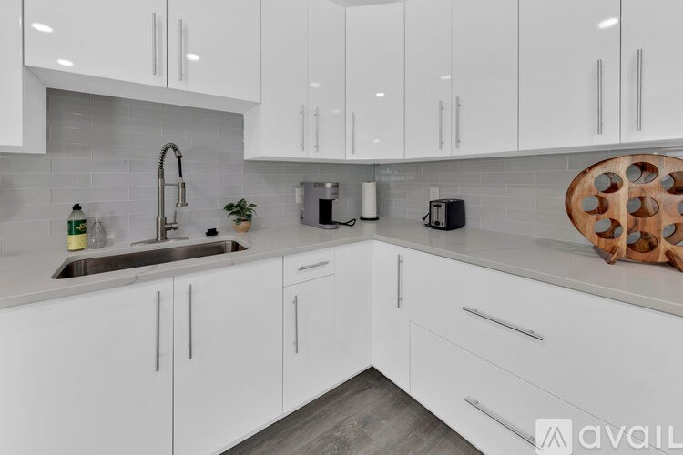 A modern kitchen with white cabinets and a wooden cutting board.