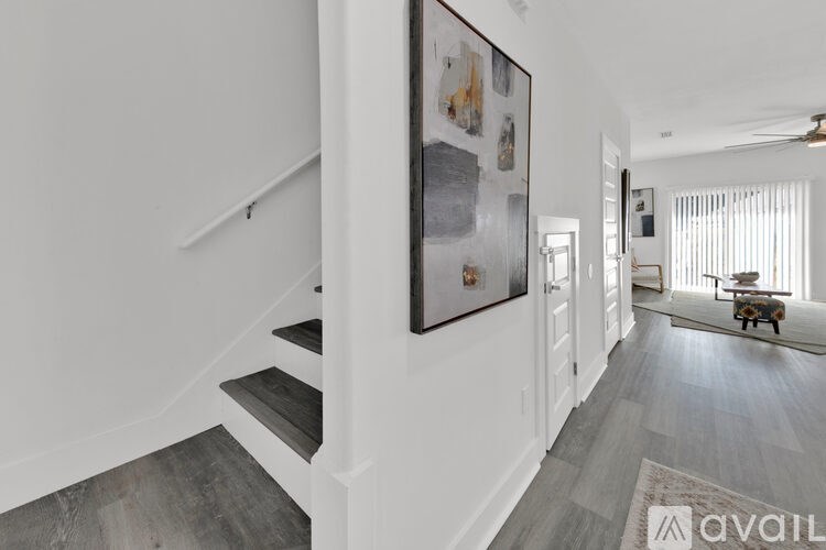 A staircase with a grey tread and white risers leads up to a white wall with a framed picture hanging on it.