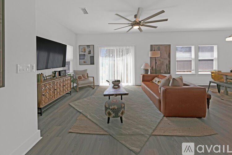 A living room with a brown couch, a coffee table, and a ceiling fan.