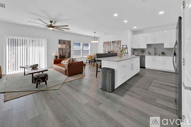 A modern kitchen with white cabinets and a wooden floor.