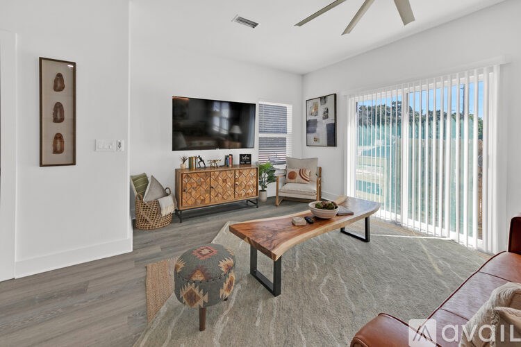 A living room with a flat screen TV, a wooden coffee table, and a brown leather couch.