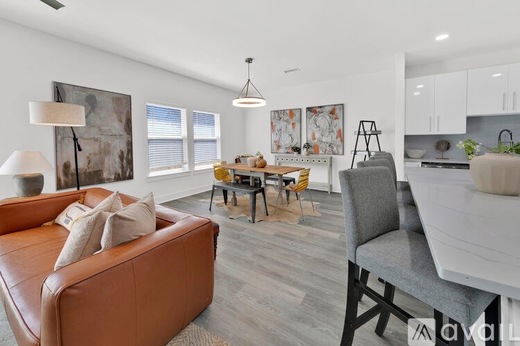A living room with a brown leather couch and a dining table with chairs.