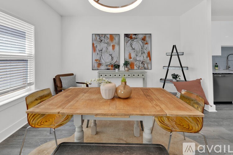 A wooden dining table with a vase and a jug on it, surrounded by chairs, in a room with a painting on the wall.