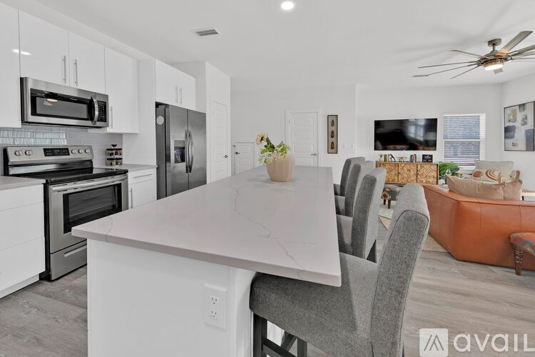A modern kitchen with a white island and grey chairs.