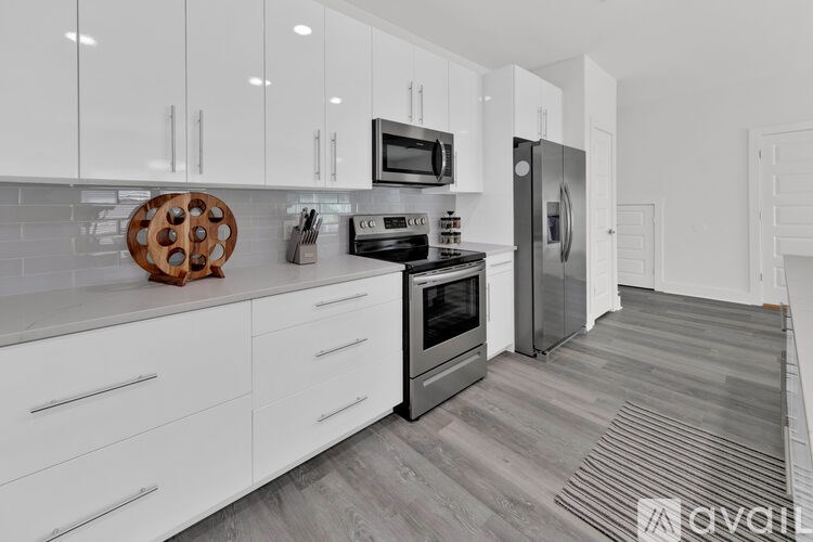 A modern kitchen with white cabinets and a wooden tray on the counter.