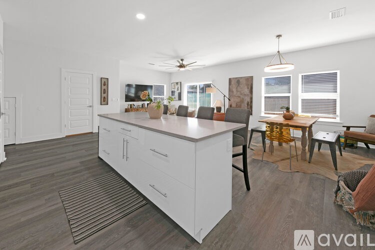 A modern kitchen with white cabinets and a wooden floor.
