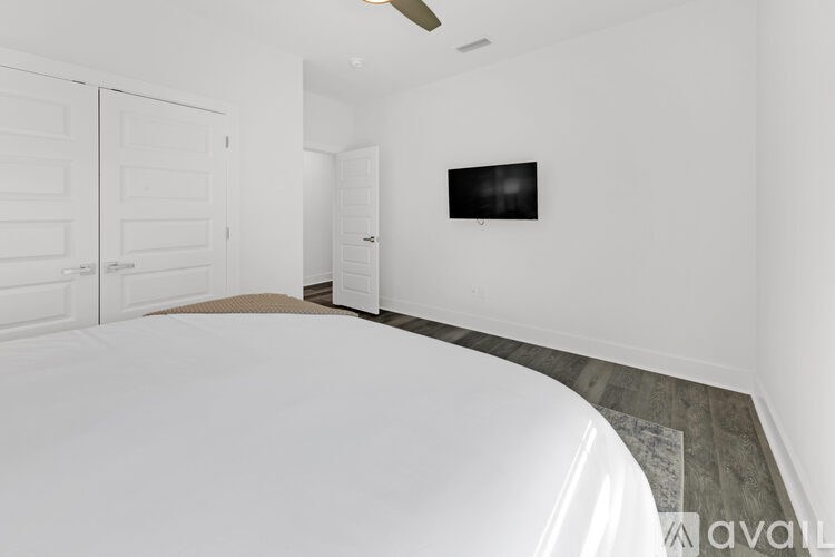 A bedroom with a large bed and a flat screen TV mounted on the wall.