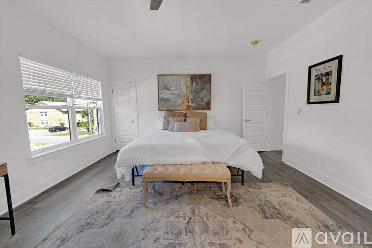 A bedroom with a large bed and a rug on the floor.