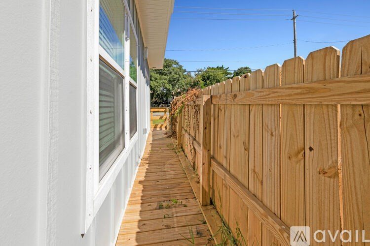A wooden fence runs along the side of a white building.