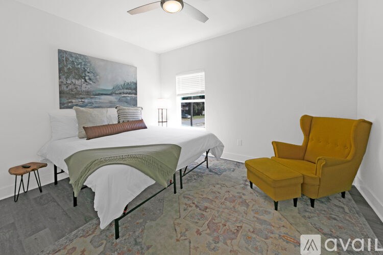 A bedroom with a bed, a chair, and a painting on the wall.