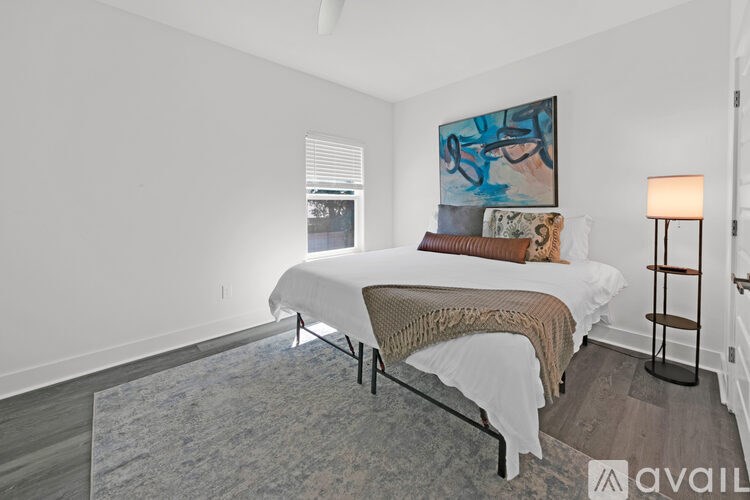 A bedroom with a large bed and a painting on the wall.