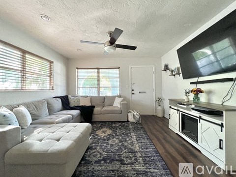 A living room with a white couch and a television mounted on the wall.