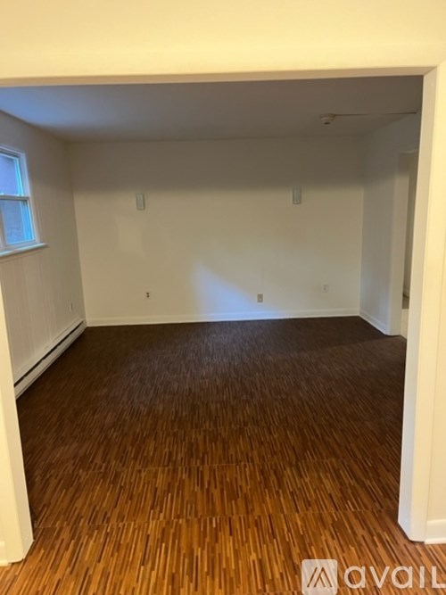 A room with wooden flooring and white walls.