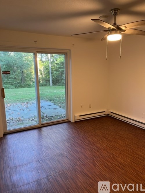 A room with a ceiling fan and sliding glass doors leading to a backyard.