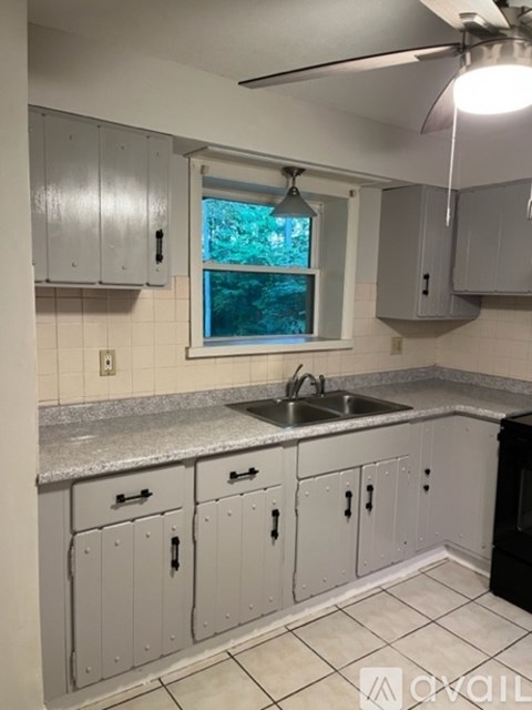 A kitchen with white cabinets and a window.