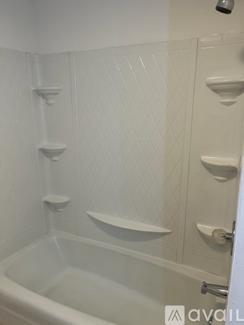 A white bathtub with a shower head and a white tiled wall.