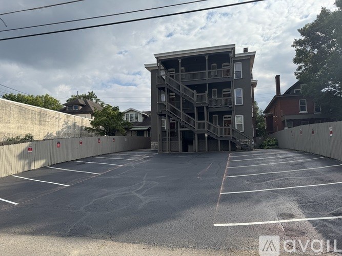 A large grey building with a balcony is surrounded by a parking lot.