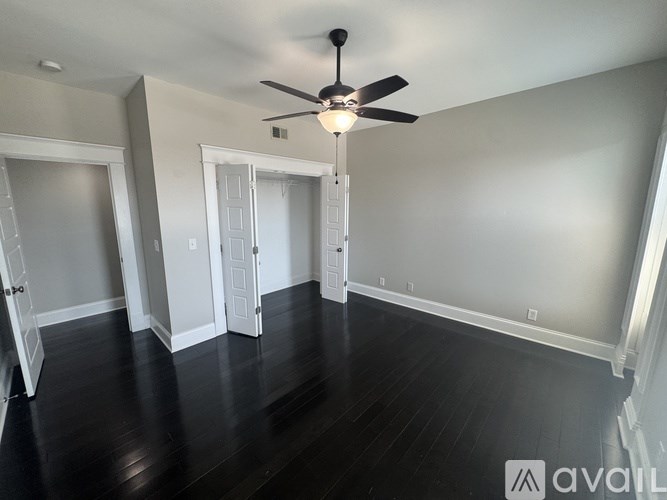 A room with a ceiling fan and wooden floors.