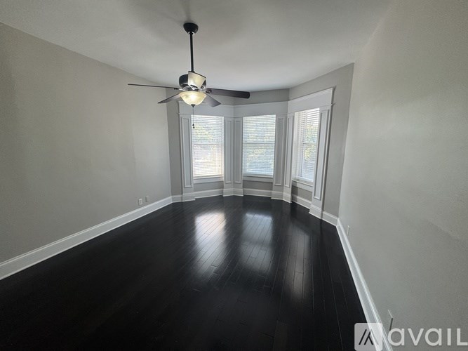 A spacious room with a ceiling fan and wooden flooring.