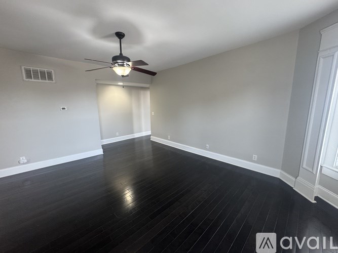 A room with a ceiling fan and wooden flooring.