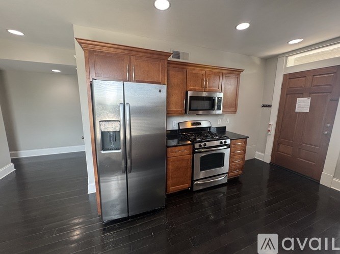 A kitchen with a stainless steel refrigerator, microwave, oven, and wooden cabinets.