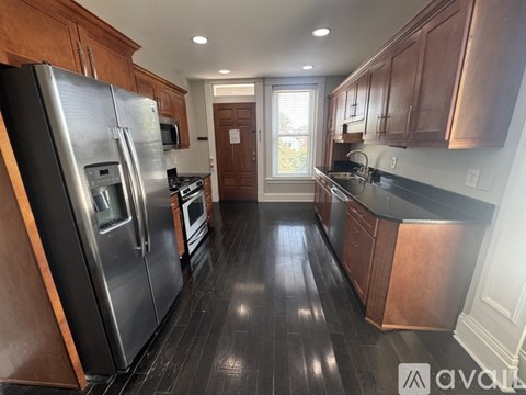 A kitchen with wooden cabinets and a black refrigerator.
