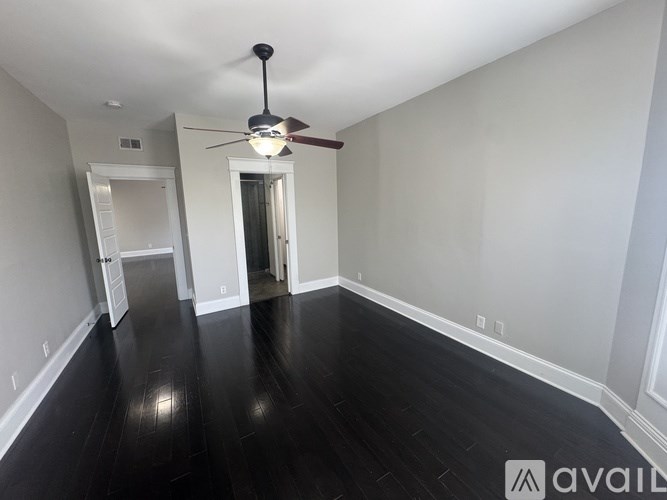A room with a ceiling fan and wooden flooring.