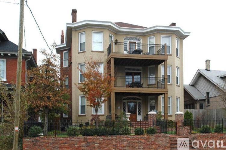 A large two-story house with a balcony and a brick wall in front.
