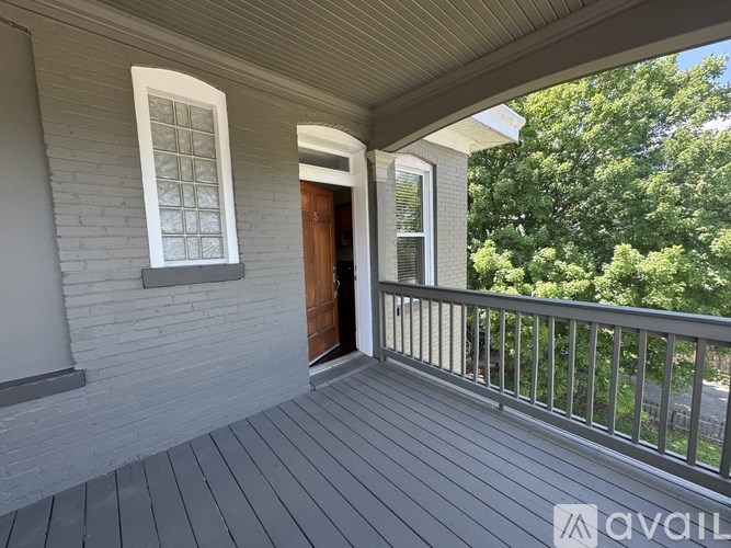 A porch with a wooden floor and a white railing.